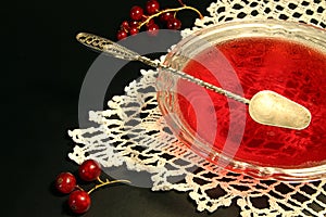 Red currant jelly in glass bowl against black background