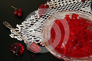 Red currant jelly in glass bowl against black background