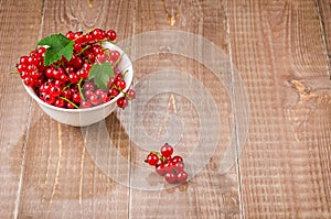 Red currant in a white bowl on a wooden background/red currant i