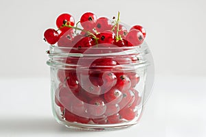Red currants close-up in a simple glass jar. White background