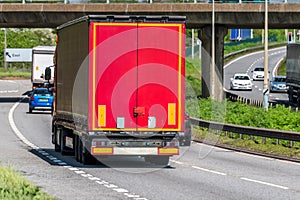 Red curtain side lorry truck on uk motorway in fast motion