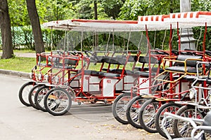 Red cyclo velomobiles with a canopy for the whole family. Parked rental tourist trike vehicles. Ecological transport for walking