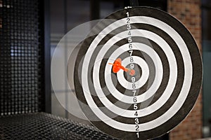 Red dart arrow hitting in the target center of dartboard on bullseye