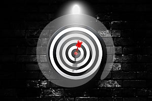 Red dart hit target on dartboard that hanging on black brick wall.