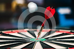 Red dart hitting bullseye on dartboard in focused shot symbolizes precise aiming and achievement