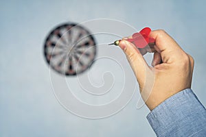 Red dart in man hand point to target on the blue wall, selective focus on dart target, concept to win