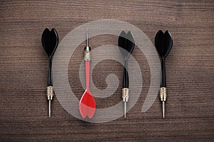 Red dart uniqueness concept on wooden background