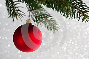 Red decorative ball on the xmas tree on glitter bokeh background. Merry christmas card.