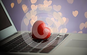 Red decorative heart on laptop, closeup. Online dating