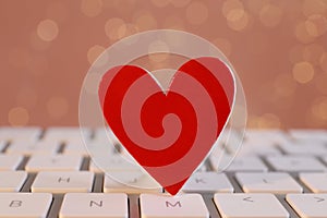 Red decorative heart on laptop keyboard, closeup. Online dating concept