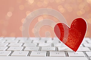 Red decorative heart on laptop keyboard, closeup. Online dating concept