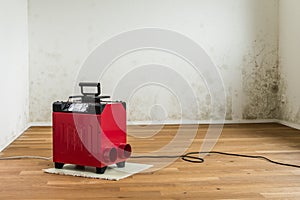 Red dehumidifier in an empty room with a toxic mold and mildew problem