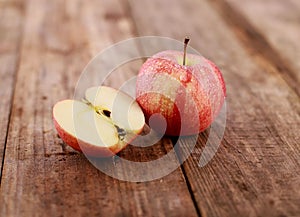 Red delicious apples and freshly sliced apple pieces on rustic wooden table   - close up