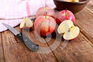 Red delicious apples and freshly sliced apple pieces on rustic wooden table   - close up