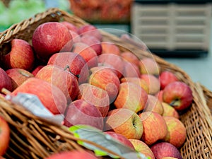 Apples in a wicker box on a grocery shelf. Close-up of fruit in a supermarket. Fresh red apples on the market counter