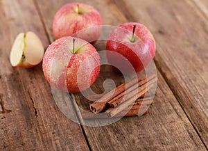 Red delicious  winter Apple with cinnamon sticks on rustic wooden table - close up