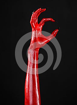 Red Devil's hands with black nails, red hands of Satan, Halloween theme, on a black background, isolated