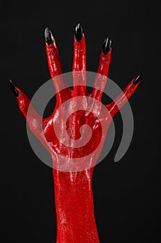 Red Devil's hands with black nails, red hands of Satan, Halloween theme, on a black background, isolated