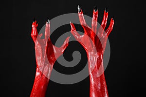 Red Devil's hands with black nails, red hands of Satan, Halloween theme, on a black background, isolated