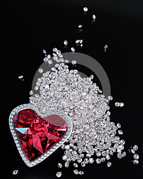 A red diamond or a large ruby in the shape of a heart, a symbol of love or Valentine`s Day. A red diamond is placed on a pile of