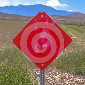 Red diamond shaped blank sign on a grassy terrain