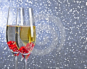 Red dice dropping in the champagne flutes on silver tint light bokeh background