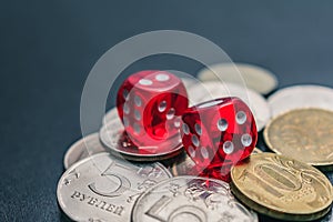 Red dice lie on different coins won at casino bets