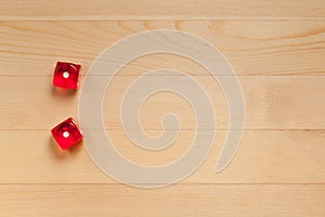 Red dice on a light brown wooden background. Discarded 2 1 and 1