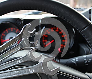 Red digits on car dashboard with soft focus on background of steel wrenches on foreground