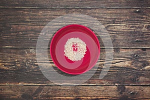 Red dish with rice on wooden table
