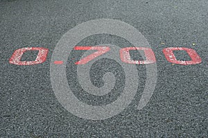 A red distance sign numbers 0.700 KM marken on surface the street in the parks