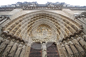 The Red Door of Gothic cathedral in West Portals Facade of Notre Dame, France, historic monuments detail ancient statue art