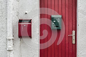 Red door near a red post box on a white facade