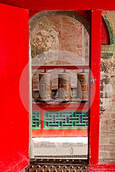 A red door with prayer wheels at the Kumbum Monastery, a Tibetan cultural monument in Xining, China