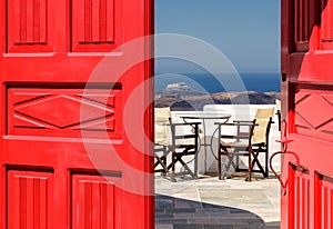Red door and view of terrace in the Greek island of Santorini.