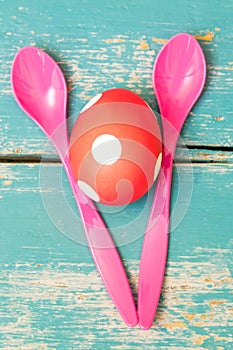 Red dotted easter egg and pink spoons on blue shabby chic background