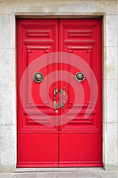 A red double door with lion head brass knockers.