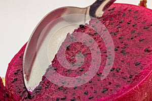 Red dragon fruit, aka Pitaia or Pitaya. Detail of a spoon cutting the pulp of a red pitaya fruit in a macro photo.