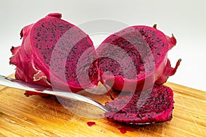 Red dragon fruit, aka Pitaia or Pitaya. Red pitaya cut in half and with a portion of the pulp in a spoon.