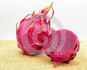 Red dragon fruit, aka Pitaia or Pitaya. Red pitayas on a jute fabric, one of the fruits being cut in half showing the fruit pulp.