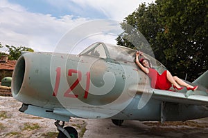 Red dress girl posing on a wing of a vintage airplane