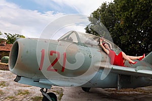 Red dress model posing on a wing of a WW2 airplane