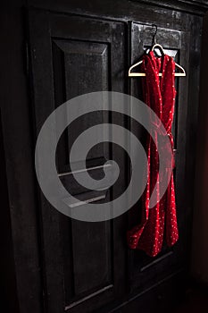 Red dress in a white dots on a wooden hanger on a black vintage wardrobe