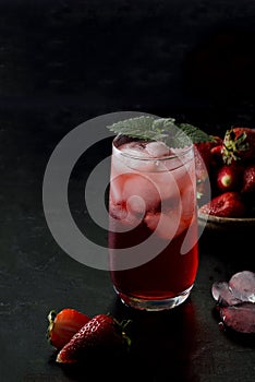 Red drink, cocktail with strawberries in a glass on a black background. Summer frozen drinks in a dark way