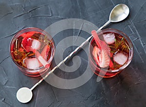 Red drink with ice. Cocktail making bar tools, strawberry and thyme leaves