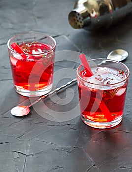 Red drink with ice. Cocktail making bar tools, strawberry and thyme leaves