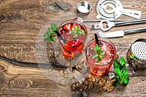Red drink with ice, mint leaves. Cocktail making bar tools