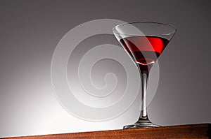 Red Drink in Martini Glass on a Wooden Surface With Gradient Background