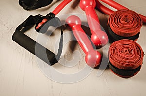 Red dumbbells, bandage and jump rope/healthy concept with red dumbbells, bandage and jump rope on a dark background. Top view