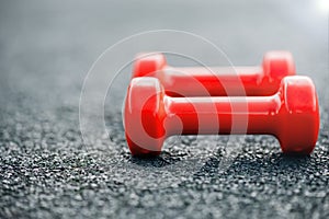 Red dumbbells on a rubberized sports field close-up. Small depth of field, background image